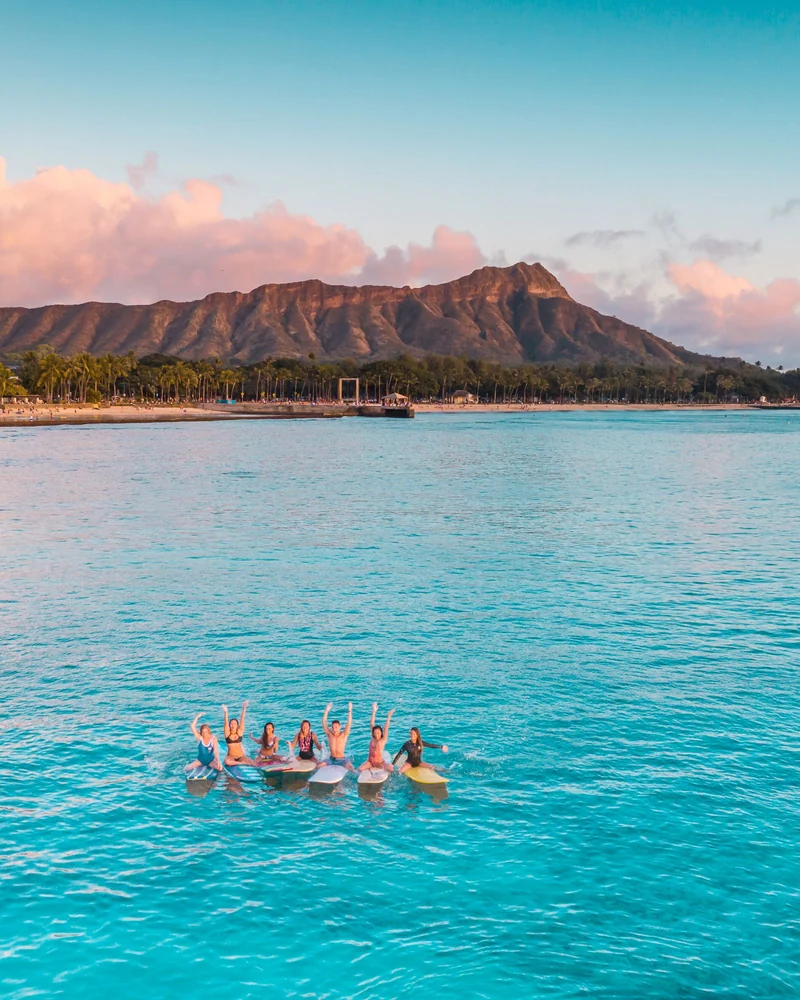 Friends sitting together on surfboards in turquoise water