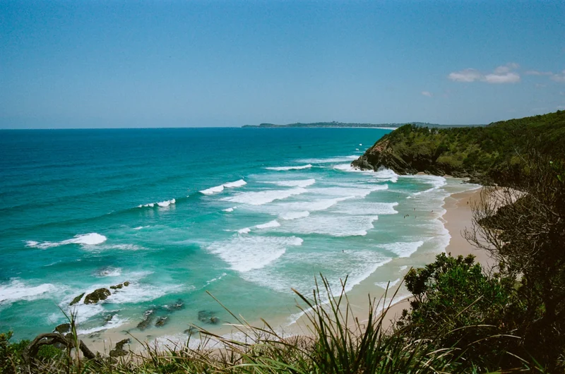 Turquoise waves rolling into a green coastal bay