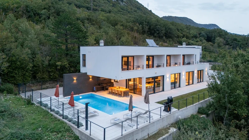 A house in Bakarac at dusk with a lit pool terrace